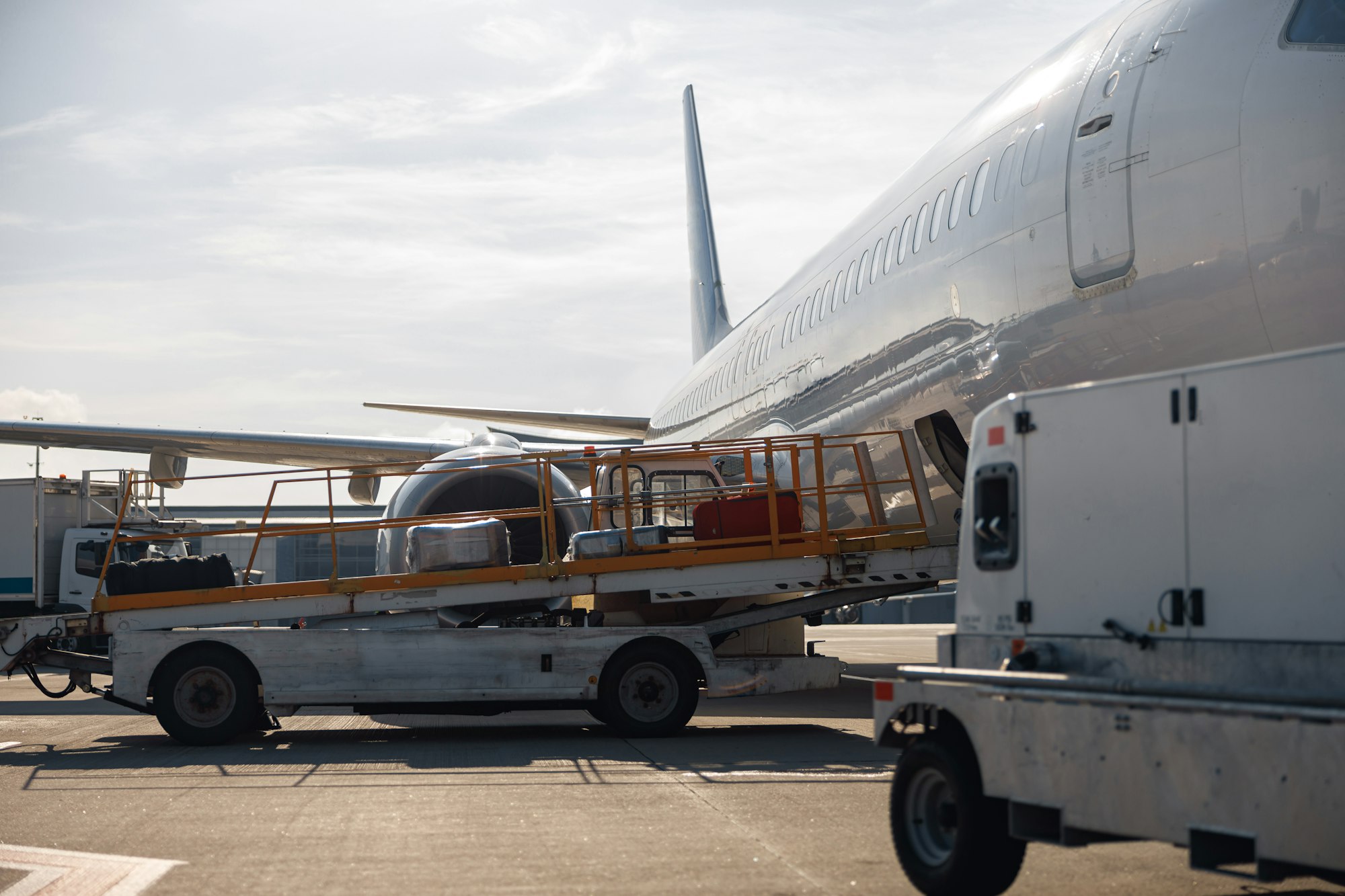 Baggage on conveyor belt unloaded from an airplane outdoors on a daytime